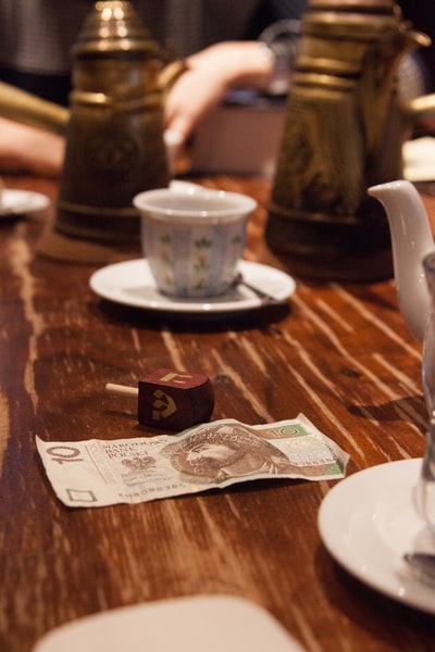 棕色木桌上白色陶瓷杯旁的20张钞票